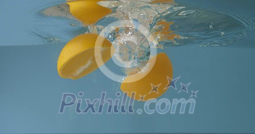 Glass aquarium with floating halves of fresh natural orange in the water with air bubles on a gray background. Slow motion 2K video. Glass aquarium with floating halves of fresh natural orange in the water with air bubles on a gray background. Slow motion 2K video.