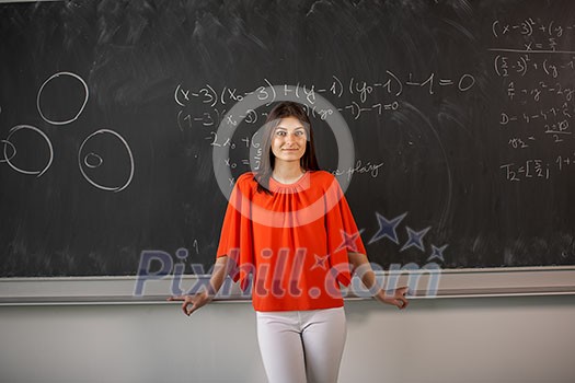 Pretty, young college student/young teacher writing on the chalkboard/blackboard during a math class Pretty, young college student/young teacher writing on the chalkboard/blackboard during a math class