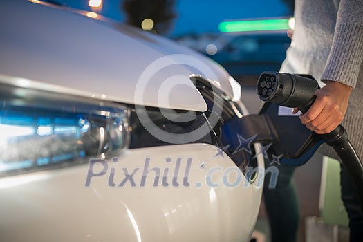 Young woman charging an electric vehicle. Car sharing concept. Young woman charging an electric vehicle. Car sharing concept.