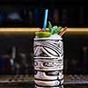 Alcoholic cocktail with lime, pomegranate and mint on a bar in a tiki bar