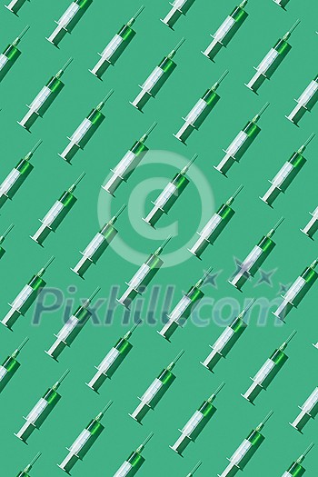 Medicinal pattern from disposable sterile plastic syringes with green vaccine or serum for injection on a light green background, with hard shadows. Medicinal pattern from disposable sterile plastic syringes with green vaccine or serum for injection on a light green background, with hard shadows.
