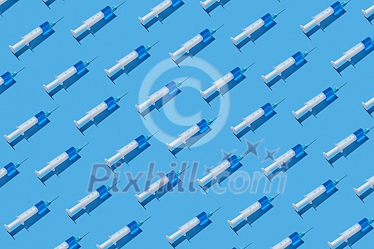 Medical diagonal pattern from disposable plastic syringes of blue serum or vaccine for an intravenous injection on a pastel blue background with hard shadow. Flat lay. Medical diagonal pattern from disposable plastic syringes of blue serum or vaccine for an intravenous injection on a pastel blue background with hard shadow. Flat lay.