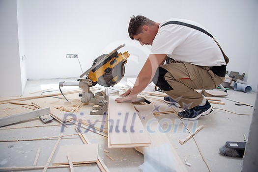 professional worker cutting plank with electrical circular saw during installation a new laminated wooden floor in a unfinished apartment professional worker cutting plank with electrical circular saw during installation a new laminated wooden floor in a unfinished apartment