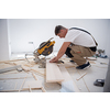 professional worker cutting plank with electrical circular saw during installation a new laminated wooden floor in a unfinished apartment