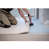 professional carpenter using rubber hammer while installing new laminated wooden floor in a unfinished apartment