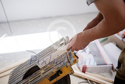 professional worker cutting plank with electrical circular saw during installation a new laminated wooden floor in a unfinished apartment professional worker cutting plank with electrical circular saw during installation a new laminated wooden floor in a unfinished apartment