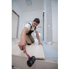 professional carpenter using rubber hammer while installing new laminated wooden floor in a unfinished apartment