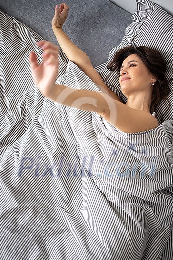 Pretty, young woman in her bed, waking up refreshed in the morning after a good night sleep, Importance of sleep concept Pretty, young woman in her bed, waking up refreshed in the morning after a good night sleep, Importance of sleep concept