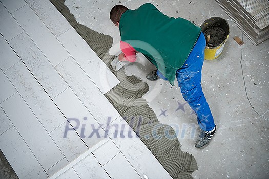 skilled worker installing the ceramic wood effect tiles on the floor Worker making laminate flooring on the construction site of the new apartment skilled worker installing the ceramic wood effect tiles on the floor Worker making laminate flooring on the construction site of the new apartment