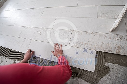 skilled worker installing the ceramic wood effect tiles on the floor Worker making laminate flooring on the construction site of the new apartment skilled worker installing the ceramic wood effect tiles on the floor Worker making laminate flooring on the construction site of the new apartment