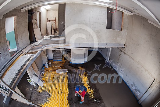 Laborer performing and polishing sand and cement screed floor on the construction site of a new two-level apartment. Sand and cement floor screed Laborer performing and polishing sand and cement screed floor on the construction site of a new two-level apartment. Sand and cement floor screed