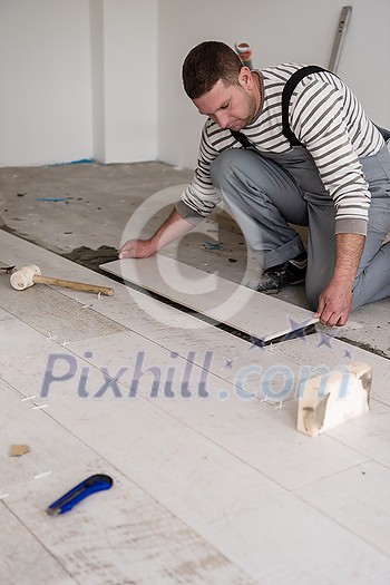 skilled worker installing the ceramic wood effect tiles on the floor Worker making laminate flooring on the construction site of the new apartment skilled worker installing the ceramic wood effect tiles on the floor Worker making laminate flooring on the construction site of the new apartment