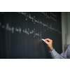 Math teacher by the blackboard during mathclass - detail of the hand with chalk