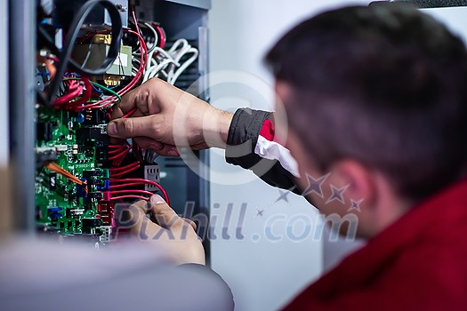 Closeup of electrician engineer working with electric cable wires of modern fuse switch box. Electrical equipment adjusting new voltage wiring Closeup of electrician engineer working with electric cable wires of modern fuse switch box. Electrical equipment adjusting new voltage wiring