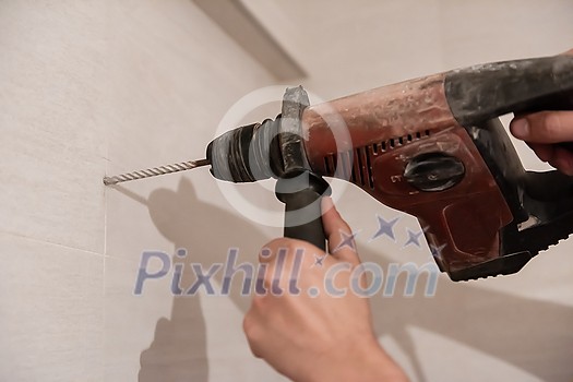 young professional construction worker drilling holes in the bathroom wall for installing bathroom accessories young professional construction worker drilling holes in the bathroom wall for installing bathroom accessories