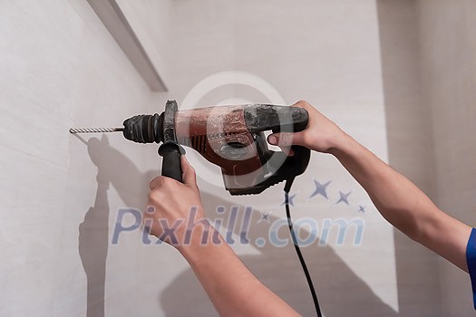 young professional construction worker drilling holes in the bathroom wall for installing bathroom accessories young professional construction worker drilling holes in the bathroom wall for installing bathroom accessories