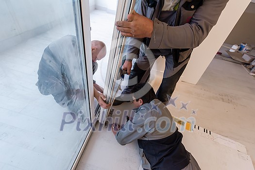 professional carpenters installing a balcony door in a new apartment with panoramic windows professional carpenters installing a balcony door in a new apartment with panoramic windows