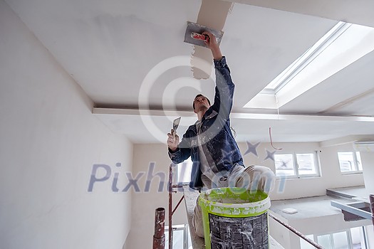 young professional construction worker using scaffold while plastering on gypsum ceiling inside the new big modern two levels apartment young professional construction worker using scaffold while plastering on gypsum ceiling inside the new big modern two levels apartment