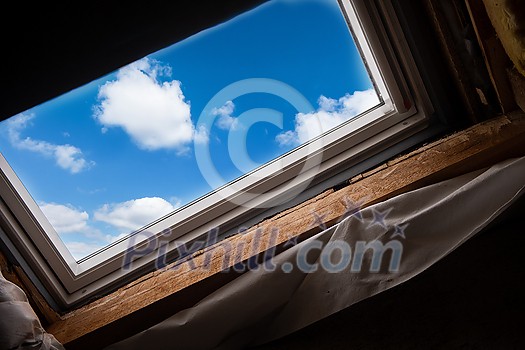 work in progress on environmentally friendly and energy efficient roof window against blue sky. Room under construction with wooden beams, boards and windows view from inside work in progress on environmentally friendly and energy efficient roof window against blue sky. Room under construction with wooden beams, boards and windows view from inside