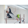 young professional construction worker using scaffold while plastering on gypsum ceiling inside the new big modern two levels apartment