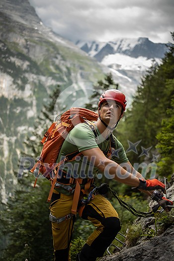 Young, male climber on a via ferrata route - climbing on a rock in Swiss Alps Young, male climber on a via ferrata route - climbing on a rock in Swiss Alps