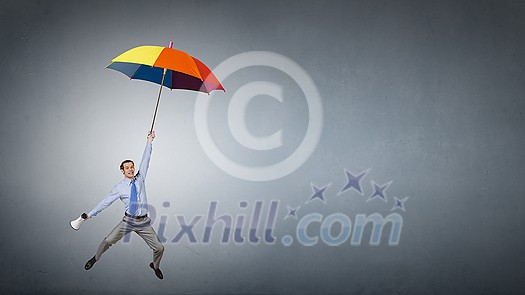 Young businessman flying high in sky on umbrella Young businessman flying high in sky on umbrella