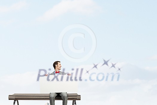 Young man sitting on bench with white banner Young man sitting on bench with white banner