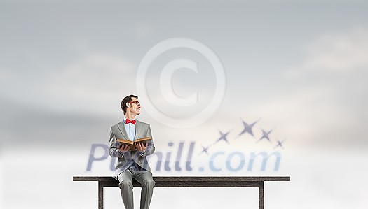 Young businessman wearing red bow tie sitting on bench with book in hands Young businessman wearing red bow tie sitting on bench with book in hands