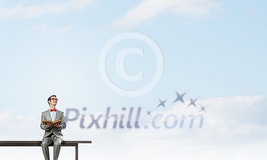 Young businessman wearing red bow tie sitting on bench with book in hands Young businessman wearing red bow tie sitting on bench with book in hands