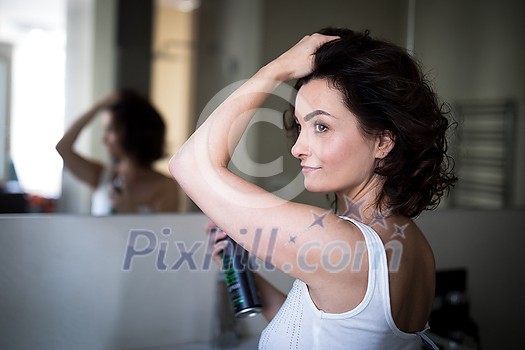 Beautiful young woman styling her her in her bathroom, in the morning Beautiful young woman styling her her in her bathroom, in the morning
