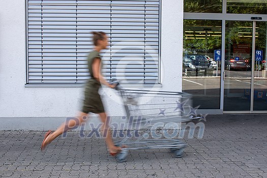 Pretty, young woman going grocery shopping with a trolley Pretty, young woman going grocery shopping with a trolley