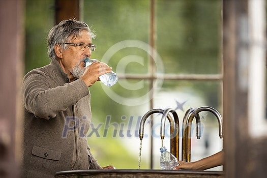 Handsome senior man drinking mineral water in a spa/health resort, enjoying its health benefits Handsome senior man drinking mineral water in a spa/health resort, enjoying its health benefits