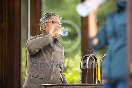 Handsome senior man drinking mineral water in a spa/health resort, enjoying its health benefits Handsome senior man drinking mineral water in a spa/health resort, enjoying its health benefits