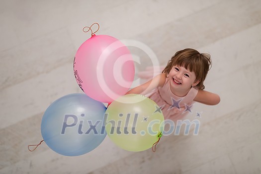 happy cute little girl in a pink dress enjoying while playing with balloons on beautiful evening near the window at home happy cute little girl in a pink dress enjoying while playing with balloons on beautiful evening near the window at home