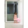 happy cute little girl in a pink dress enjoying while playing with balloons on beautiful evening near the window at home