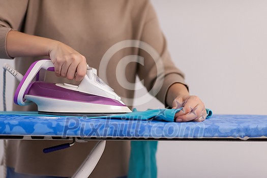 beautiful young red haired housewife in good mood ironing clothes on ironing board in front of a white wall at home beautiful young red haired housewife in good mood ironing clothes on ironing board in front of a white wall at home