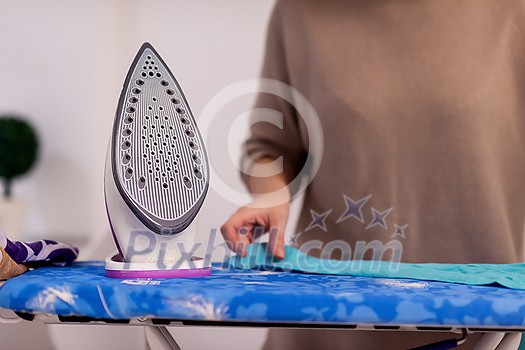 beautiful young red haired housewife in good mood ironing clothes on ironing board in front of a white wall at home beautiful young red haired housewife in good mood ironing clothes on ironing board in front of a white wall at home