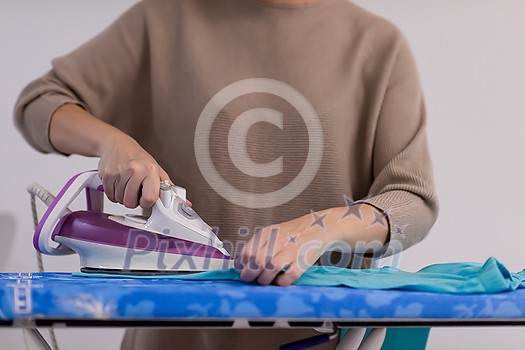 beautiful young red haired housewife in good mood ironing clothes on ironing board in front of a white wall at home beautiful young red haired housewife in good mood ironing clothes on ironing board in front of a white wall at home