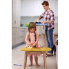 happy family spending time together at home  cute little daughter in a pink dress playing and painting the jewelry box while young redhead mother ironing clothes behind her