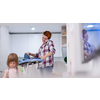 happy family spending time together at home  cute little daughter in a pink dress playing and painting the jewelry box while young redhead mother ironing clothes behind her