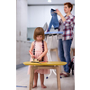 happy family spending time together at home  cute little daughter in a pink dress playing and painting the jewelry box while young redhead mother ironing clothes behind her