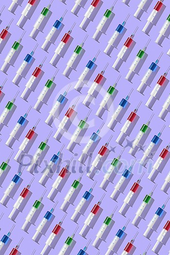 Vertical medicinal pattern from plastic disposable syrenges with red, blue and green liquid on a pastel lavender background. Flat lay. Vertical medicinal pattern from plastic disposable syrenges with red, blue and green liquid on a pastel lavender background. Flat lay.