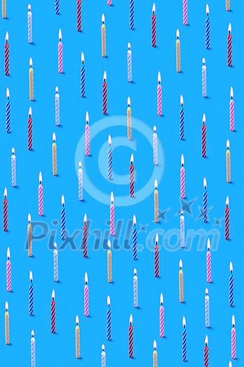 Decorative congratulation composition from multicolored bithday candles for sweet dessert on a blue background. Birthday party card. Decorative congratulation composition from multicolored bithday candles for sweet dessert on a blue background. Birthday party card.