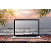 Notebook monitor with blurred seascape sunrise picture on a wooden table against the same background with green palm leaves frame, copy space. Working at sea, outside office concept.