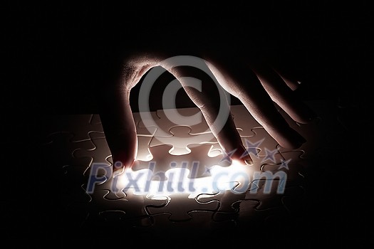 Hand connecting missing jigsaw glowing puzzle piece Hand connecting missing jigsaw glowing puzzle piece