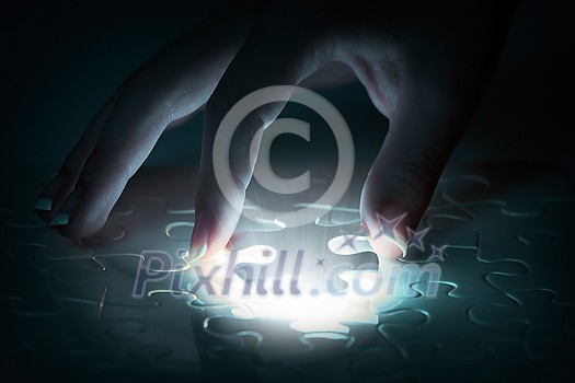 Hand connecting missing jigsaw glowing puzzle piece Hand connecting missing jigsaw glowing puzzle piece