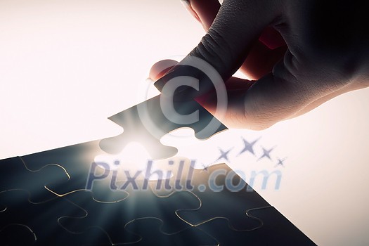 Hand connecting missing jigsaw glowing puzzle piece Hand connecting missing jigsaw glowing puzzle piece