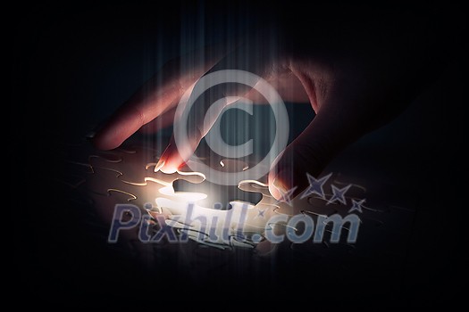 Hand connecting missing jigsaw glowing puzzle piece Hand connecting missing jigsaw glowing puzzle piece