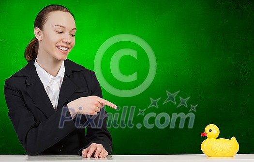 Young businesswoman pointing with finger at yellow rubber duck toy on table Young businesswoman pointing with finger at yellow rubber duck toy on table