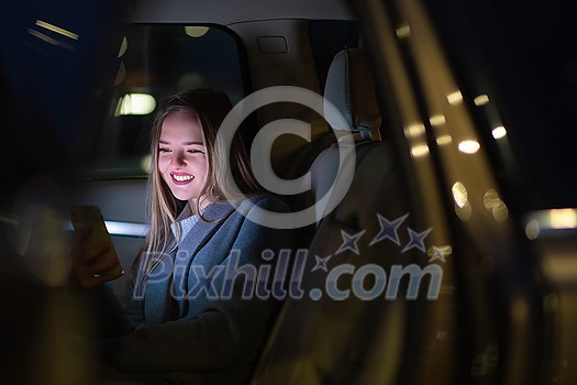 Young woman with her cell phone sitting in the backseat of a car, getting ready to travel (color toned image; shallow DOF) Young woman with her cell phone sitting in the backseat of a car, getting ready to travel (color toned image; shallow DOF)